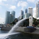 シンガポールのマーライオン像から噴き出る噴水と背後にそびえる超高層ビルの風景